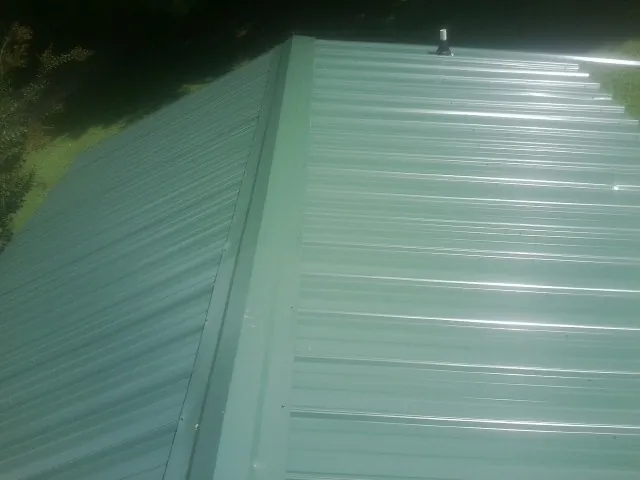 New green metal panels meeting at the ridge of a roof — Flat Roof Repair work by our crew in Cedar Key