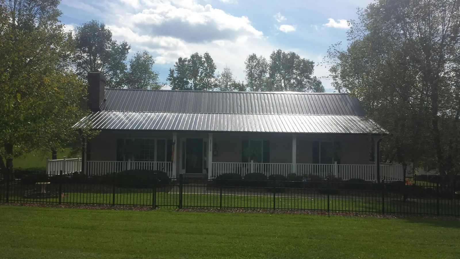 Gray metal roof on a brick ranch with a full width front porch — Gutter Guard Installation work by our crew in Cedar Key