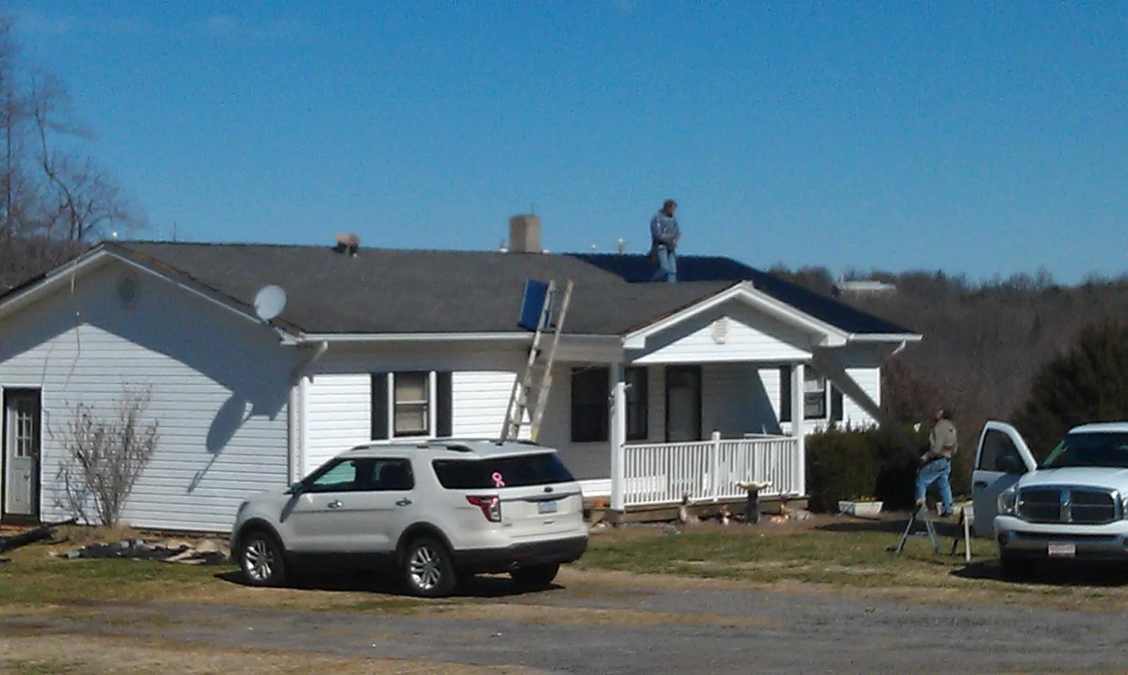 Roofers stripping shingles from a white ranch house roof in Cedar Key